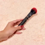 Brocha vibrador Blushy sostenida en la mano, diseño ergonómico y discreto